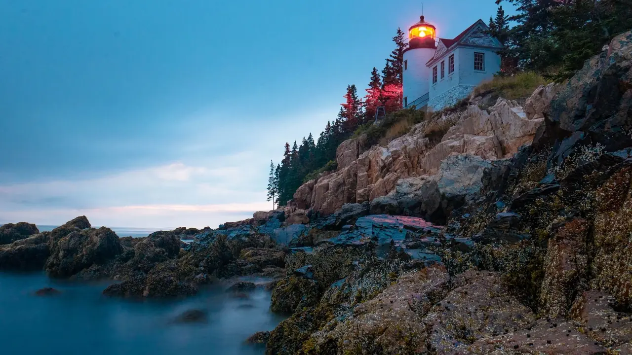 Bass Harbor Head Lighthouse perched on pink granite cliffs above the sea at dusk in Acadia National Park, Maine