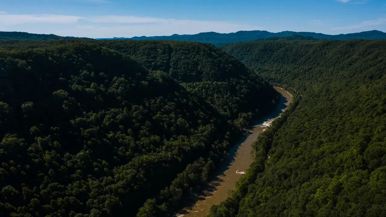 Aerial view of a river winding through a deep, densely forested gorge in the Appalachian hills