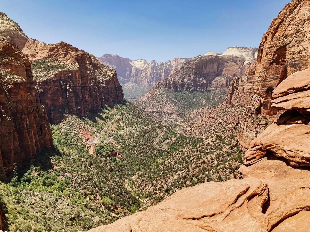 View down Zion Canyon from the Canyon Overlook, with red sandstone cliffs and switchbacks winding through the green valley